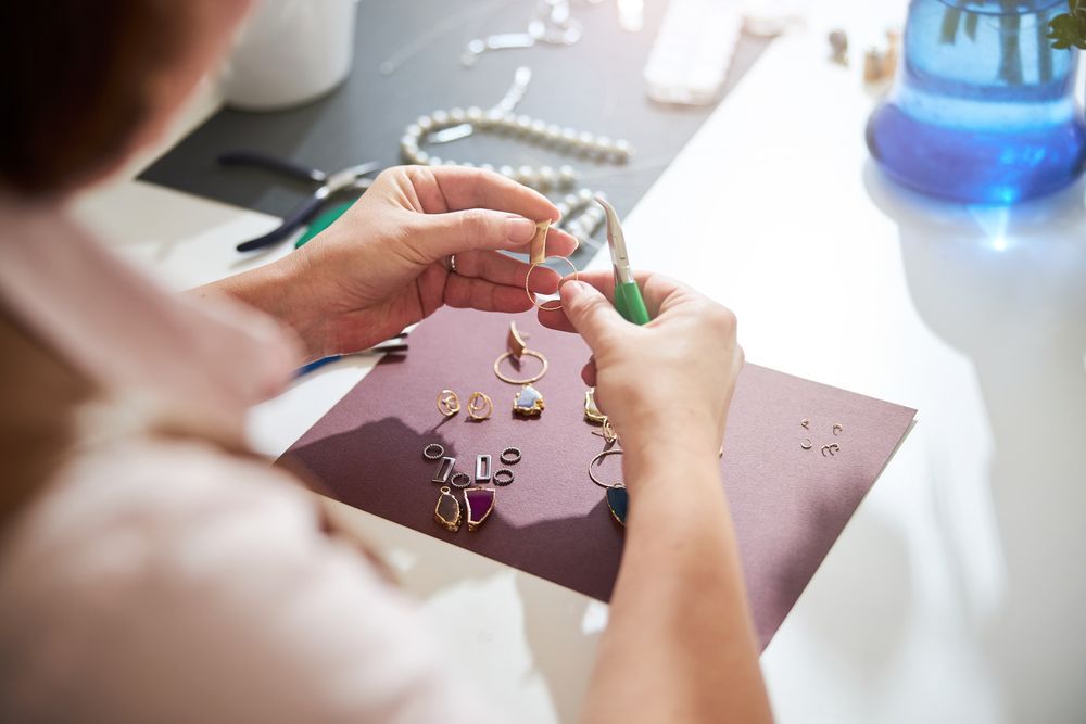 Una mujer está haciendo un collar con un par de alicates.