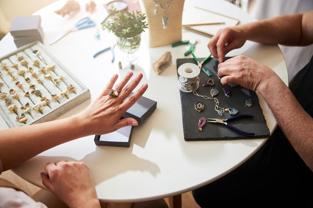 Un hombre y una mujer están sentados en una mesa haciendo joyas.