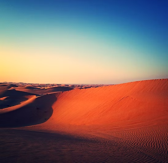 Eine Sanddüne in der Wüste mit einem blauen Himmel im Hintergrund