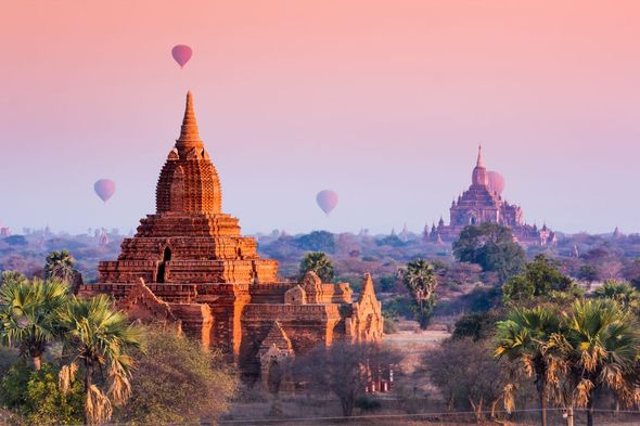 Im Hintergrund fliegen Heißluftballons über einem Tempel.