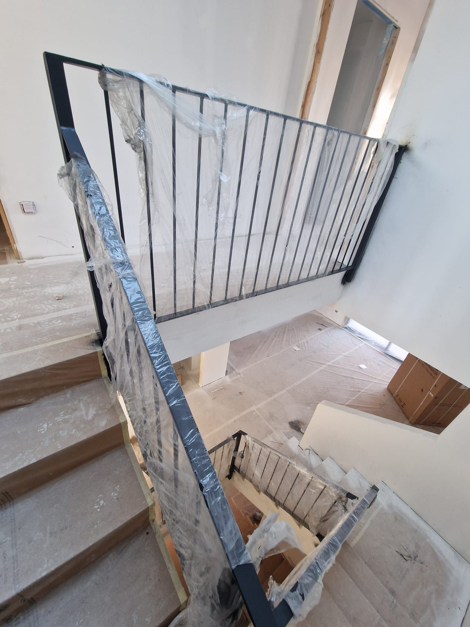 Escalera con peldaños de hormigón y barandillas metálicas azules en el interior de un edificio en construcción
