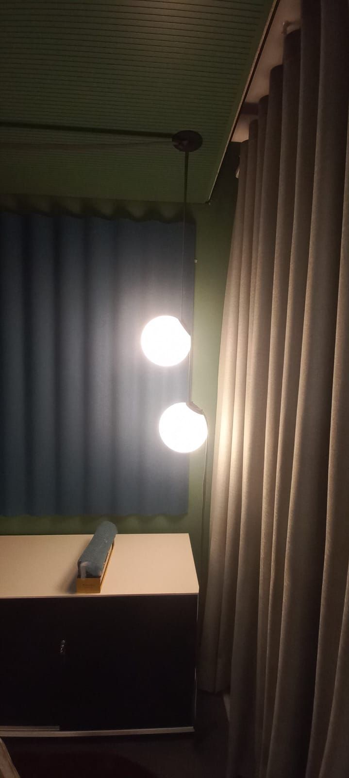 Una lámpara cuelga del techo en una habitación con cortinas.