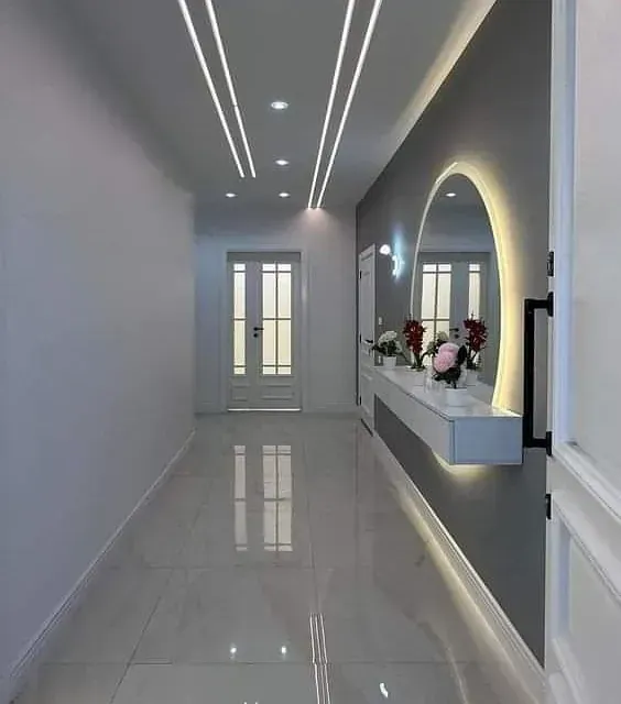 Un pasillo con un espejo y flores en la pared.