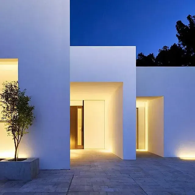 Un edificio blanco con un árbol delante.