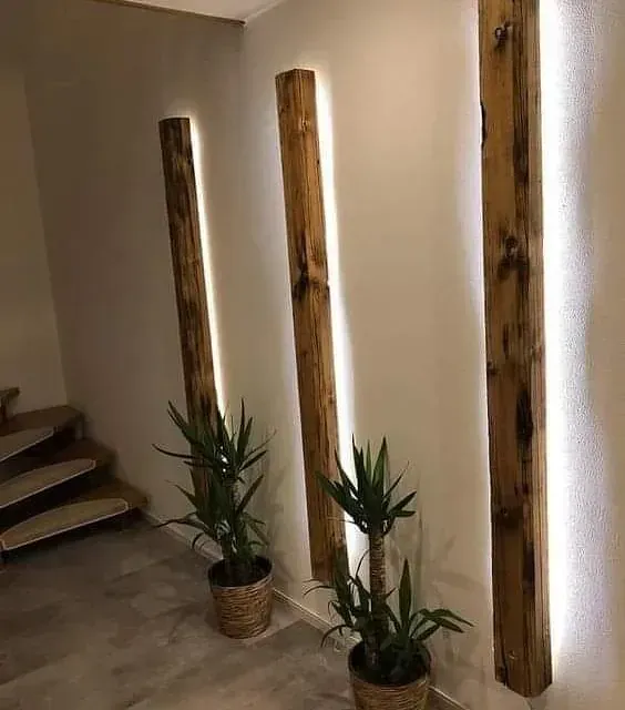 Dos plantas en macetas están sentadas una al lado de la otra en un pasillo al lado de una escalera.