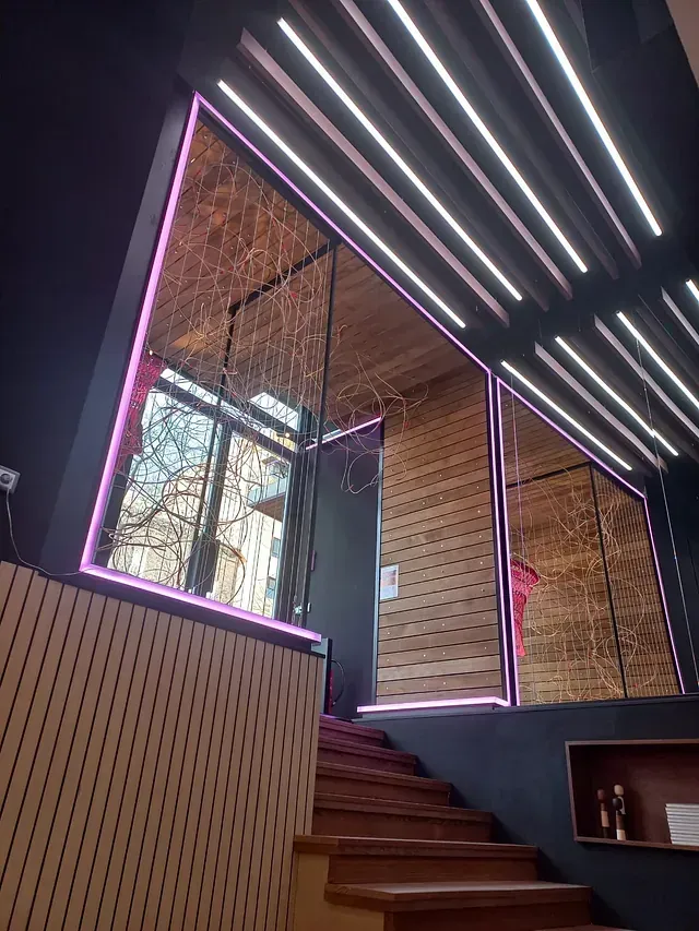 Una habitación con escaleras y una ventana con una luz rosada.