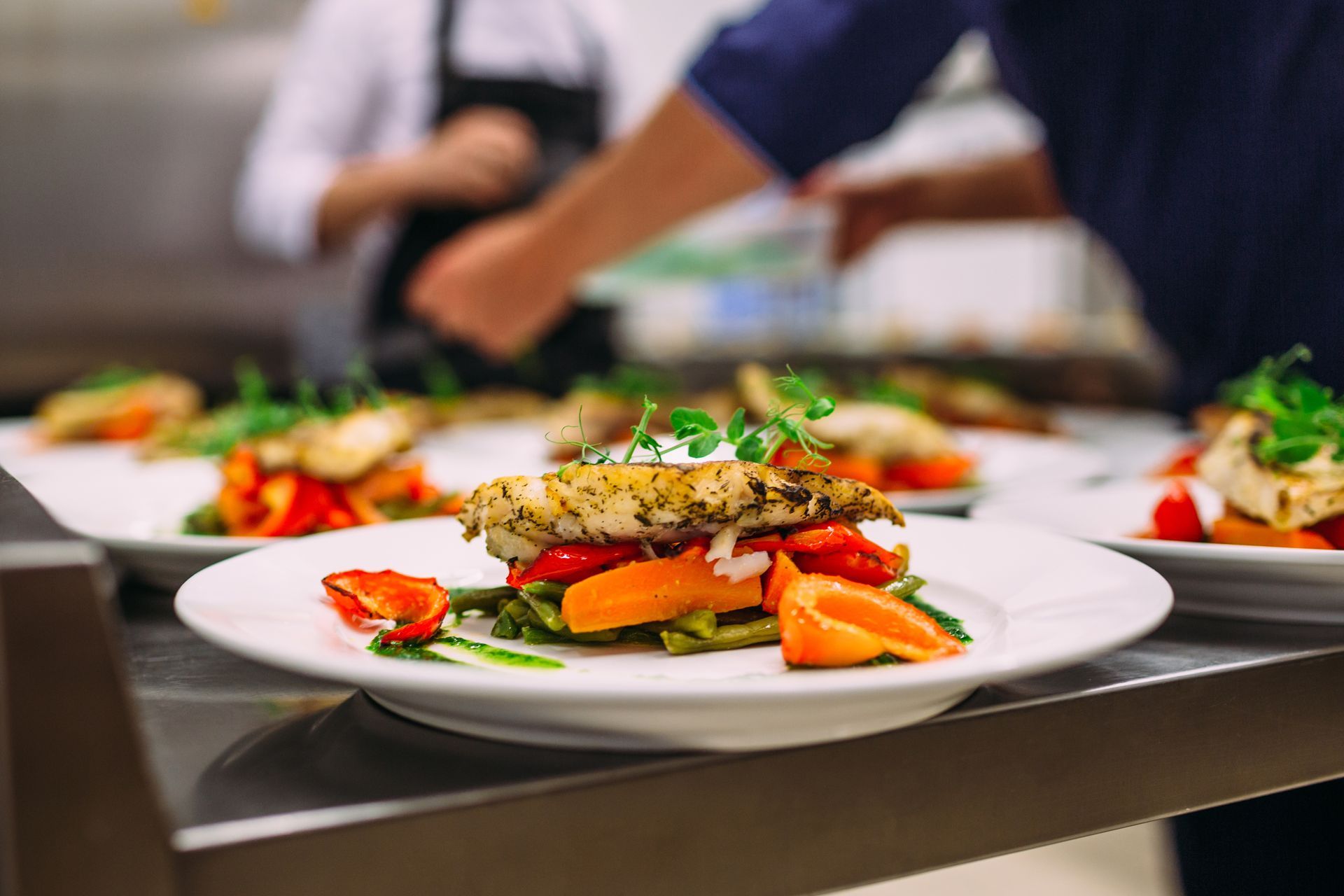 Plat de poulet gastronomique accompagné de légumes colorés, en cours de préparation en cuisine.