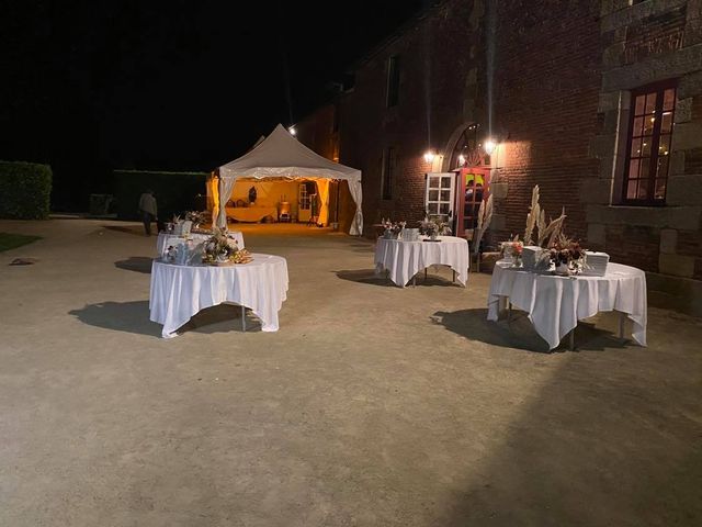 Banquet extérieur Événement en extérieur en soirée : trois tables avec de la nourriture, une tente éclairée en arrière-plan, un bâtiment en briques.