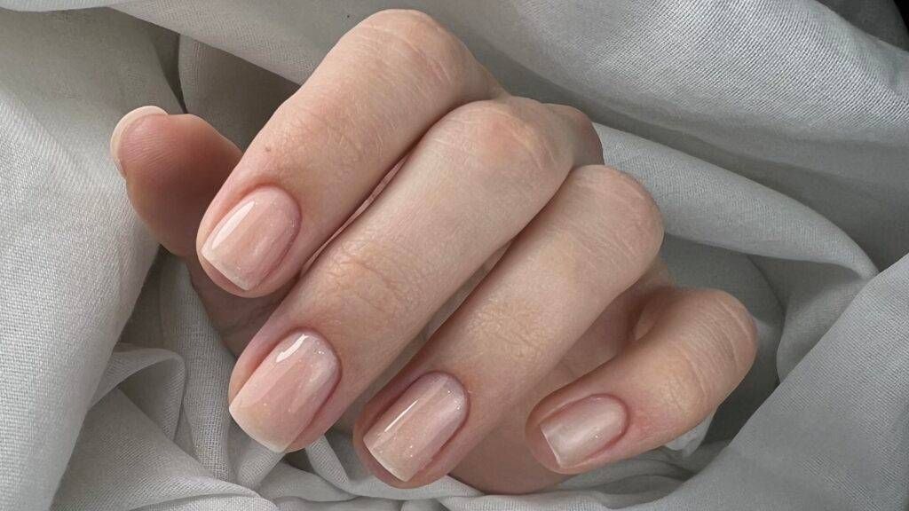 Eine Nahaufnahme der Nägel einer Person auf einem weissen Tuch. Foto von Fusspflege Pohl