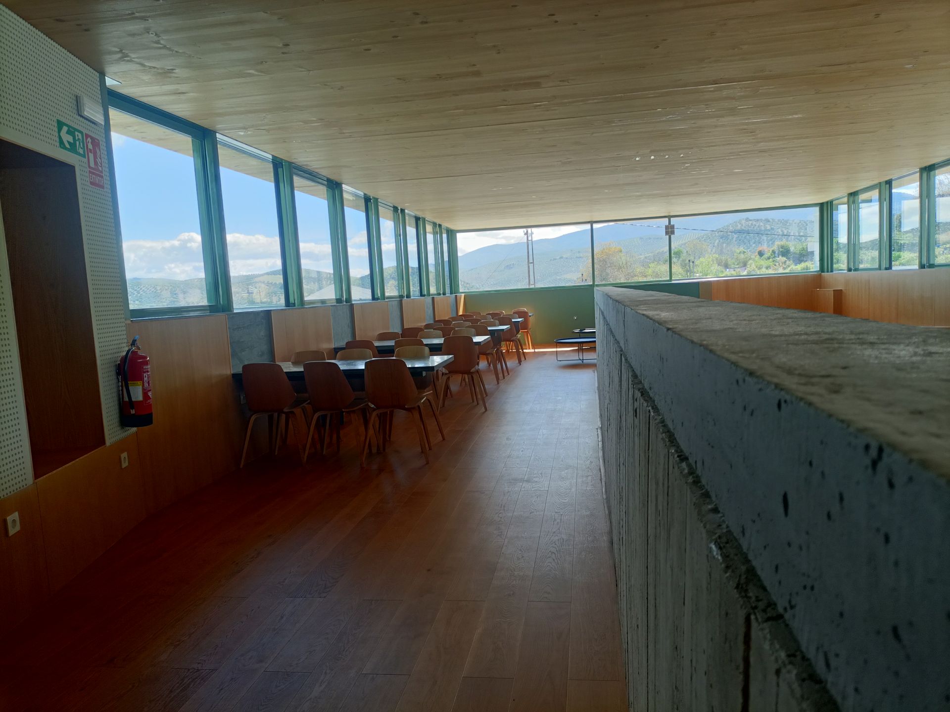 Un largo pasillo con mesas y sillas en un edificio.