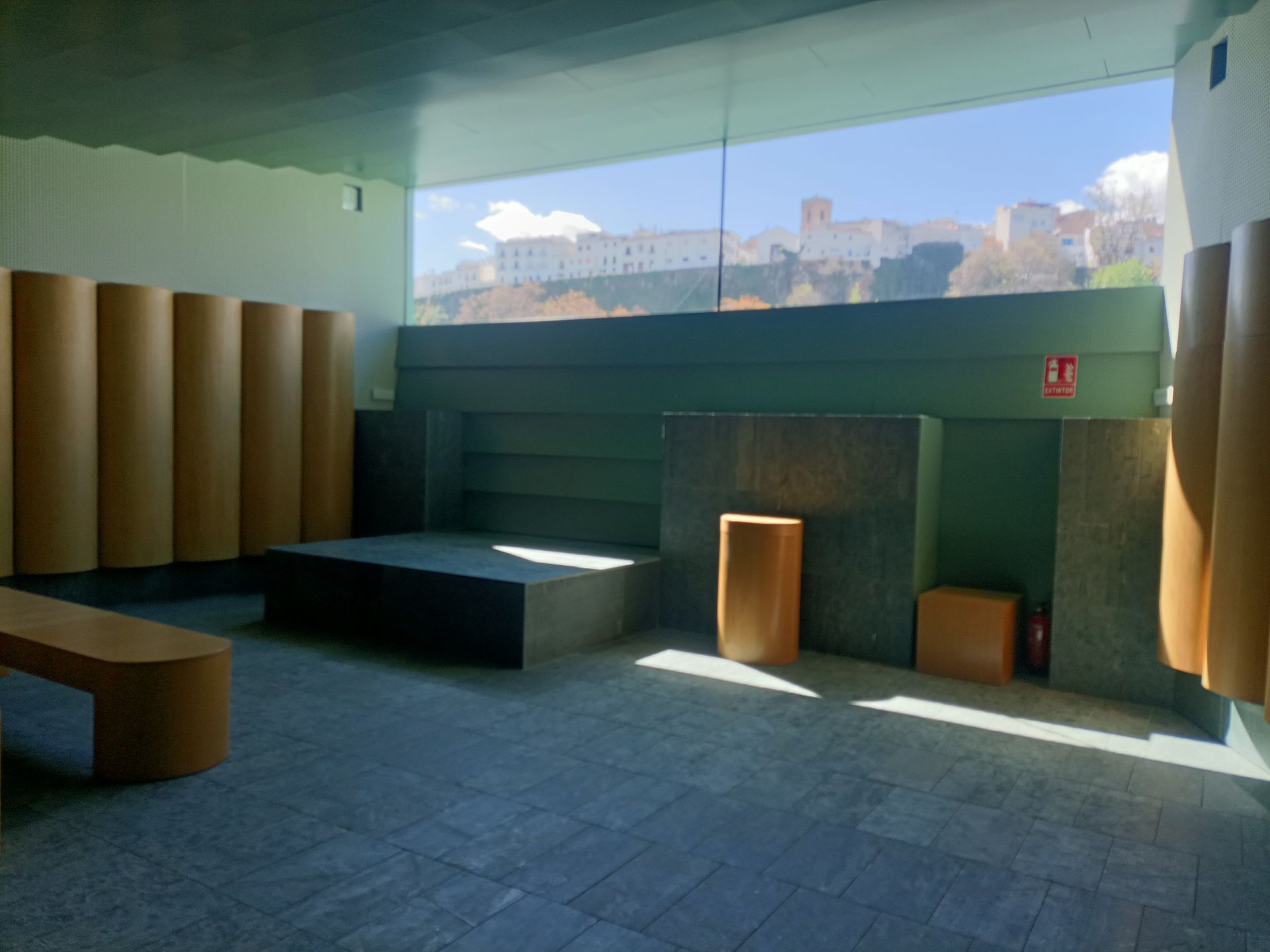 Una habitación vacía con una gran ventana y un banco de madera.