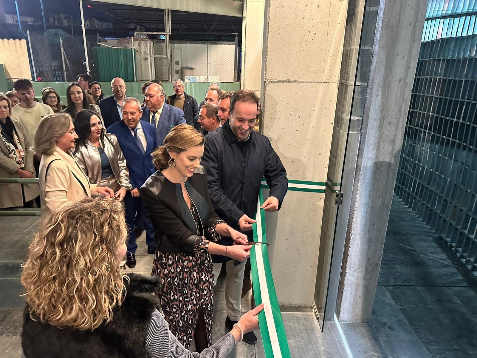 Un grupo de personas está cortando una cinta verde en una habitación.