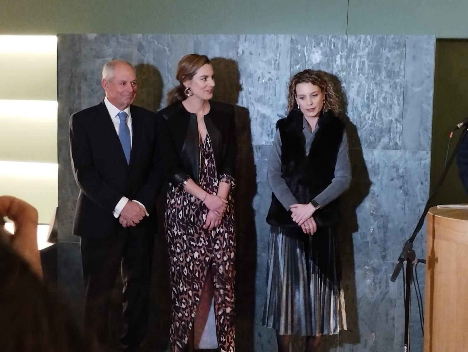 Un hombre con traje y corbata está junto a dos mujeres.