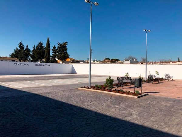Un estacionamiento con una pared blanca y algunos bancos.