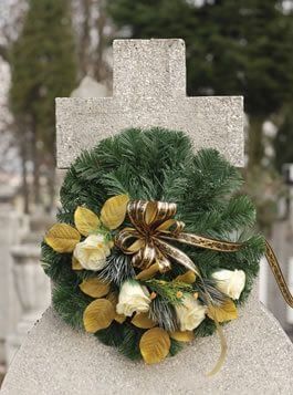 Una corona de flores está colocada encima de una tumba en un cementerio.