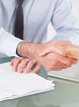 Un hombre y una mujer se dan la mano sobre una mesa.