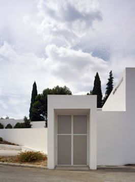 Un edificio blanco con una puerta y árboles al fondo.