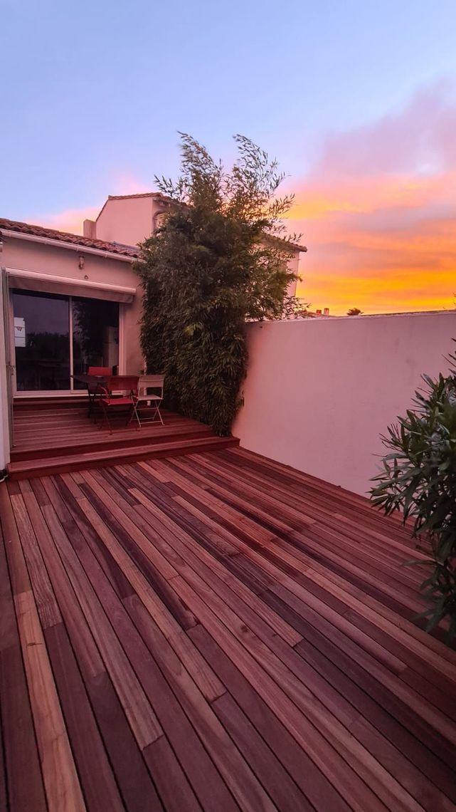 Une terrasse en bois avec un coucher de soleil