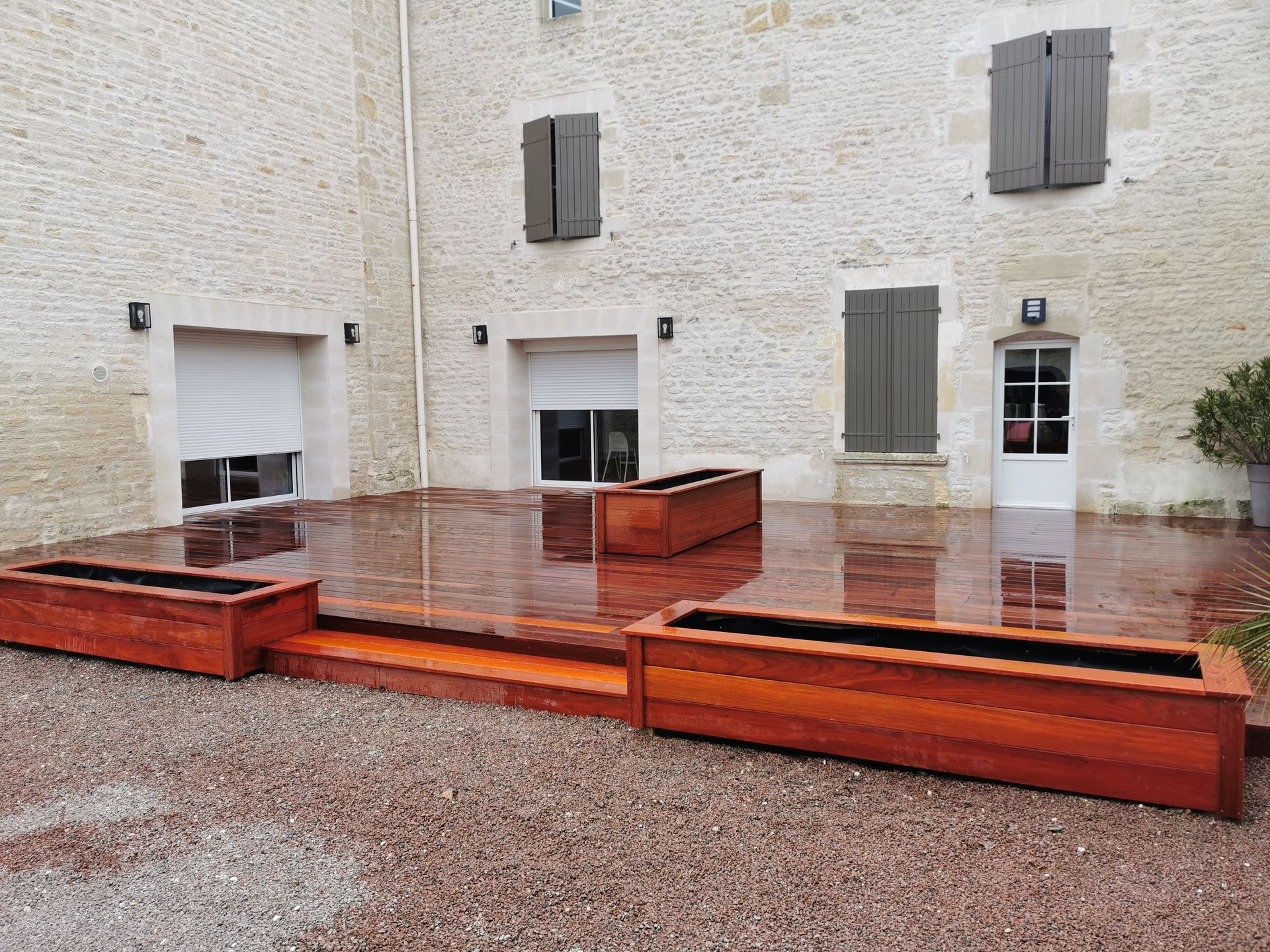 Une terrasse en bois devant une maison en pierre