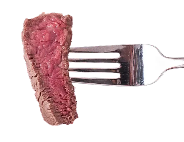 Un trozo de carne está en un tenedor sobre un fondo blanco.