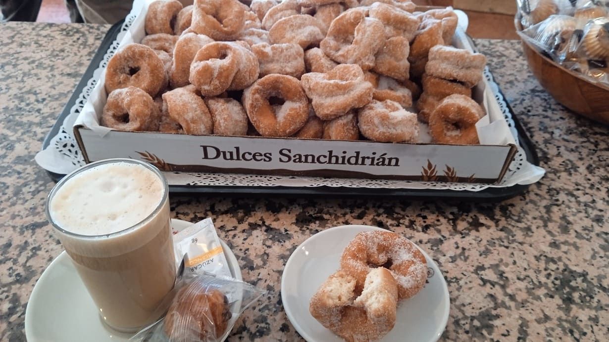 Una caja de donas y una taza de café sobre una mesa.