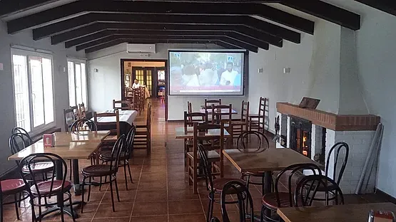 Una sala grande con mesas y sillas y una pantalla de proyección.