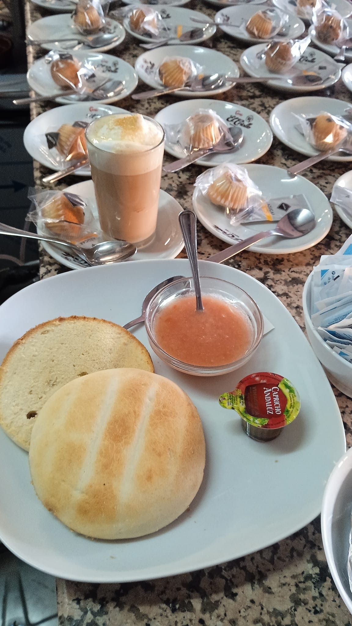 Un plato blanco cubierto con pan, una taza de café y un tazón de salsa.