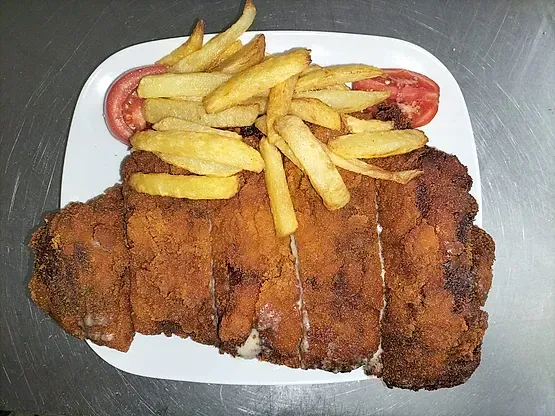 Un plato de carne frita y patatas fritas en una mesa.