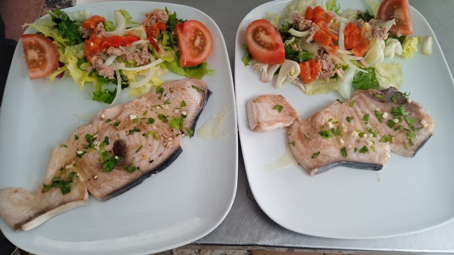 Dos platos de comida con carne y verduras en una mesa.
