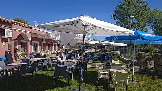 Un restaurante con mesas, sillas y sombrillas en el césped.