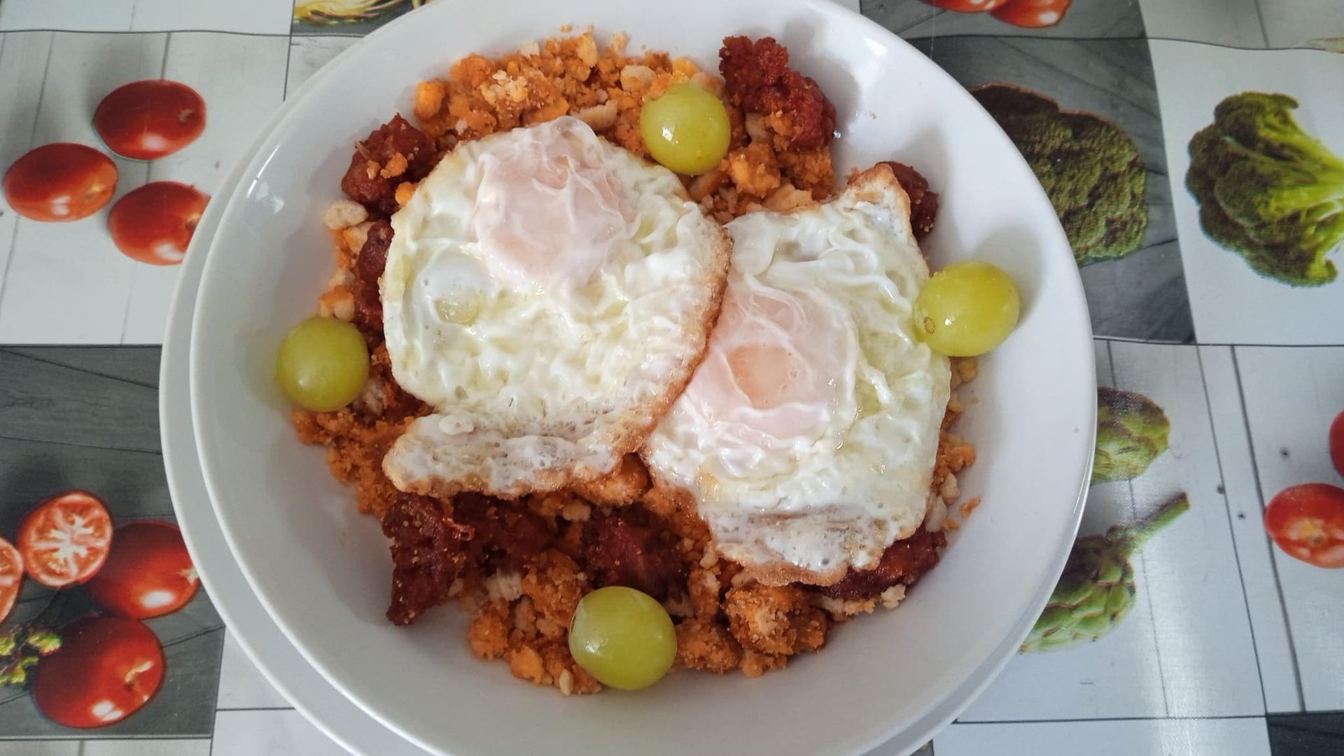 Un tazón de comida con huevos y uvas sobre una mesa.