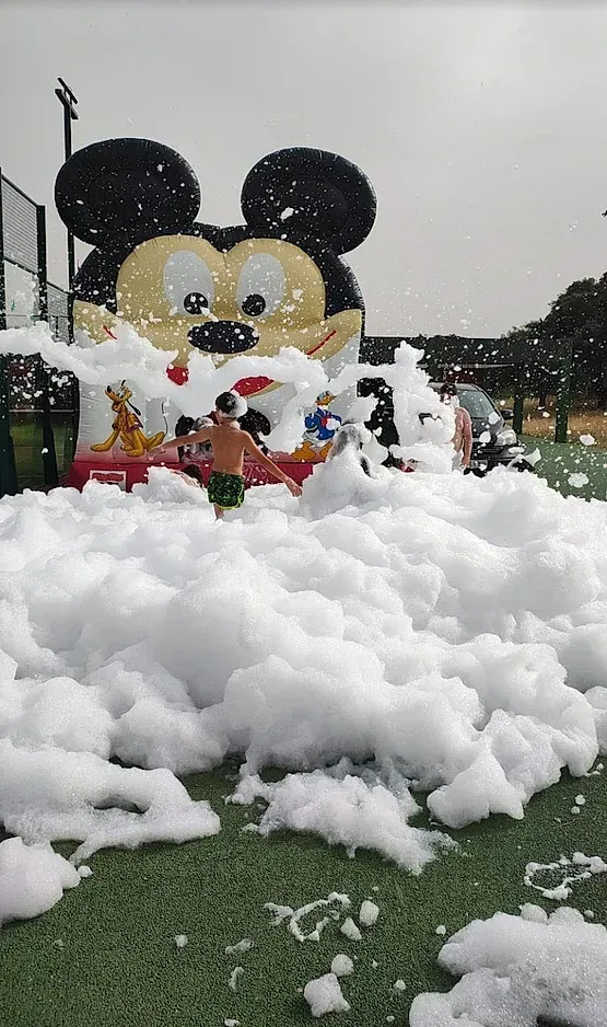 Un inflable de Mickey Mouse está cubierto de espuma en un campo.