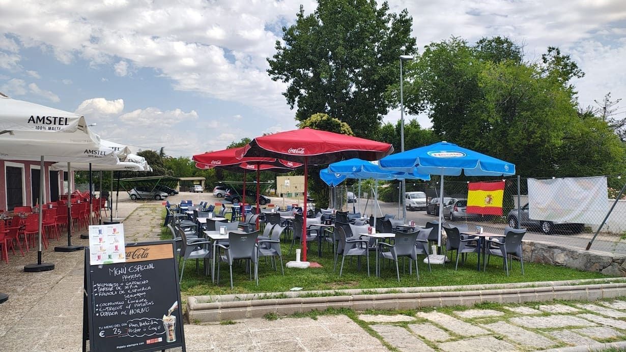 Un restaurante con mesas, sillas y sombrillas en el césped.
