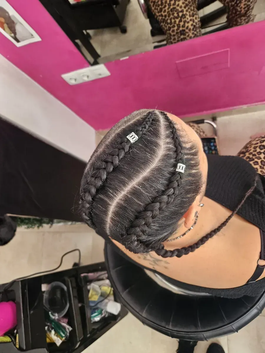 Primer plano de la cabeza de una persona con trenzas cuidadosamente trenzadas, algunas adornadas con cuentas blancas.