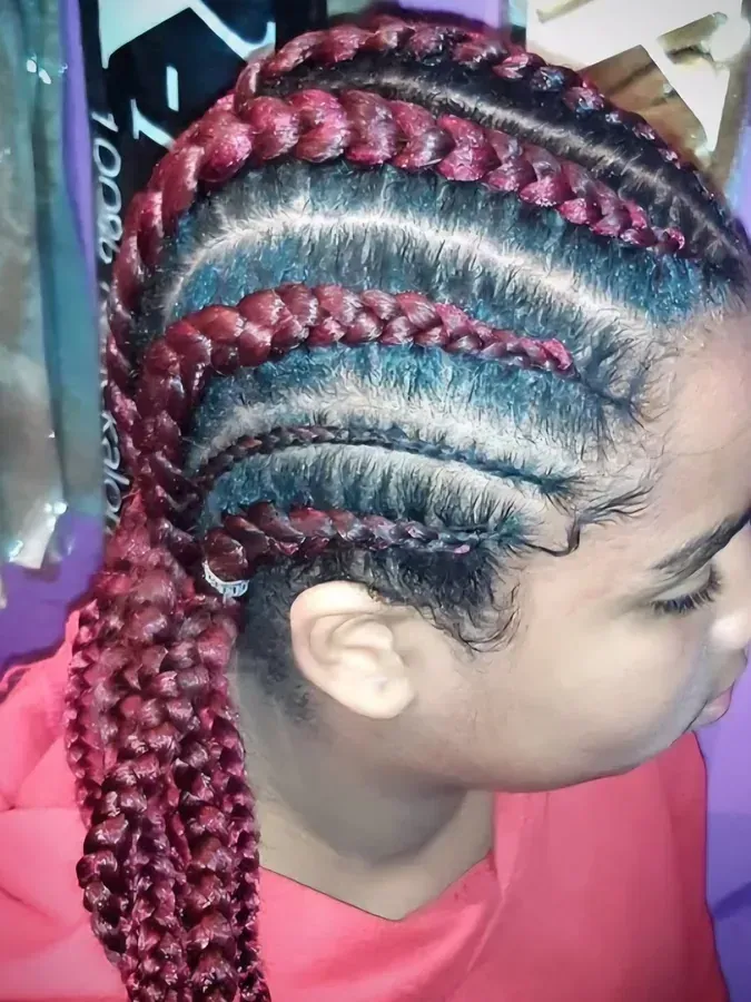Peinado trenzado rojo con trenzas africanas sobre cabello oscuro.