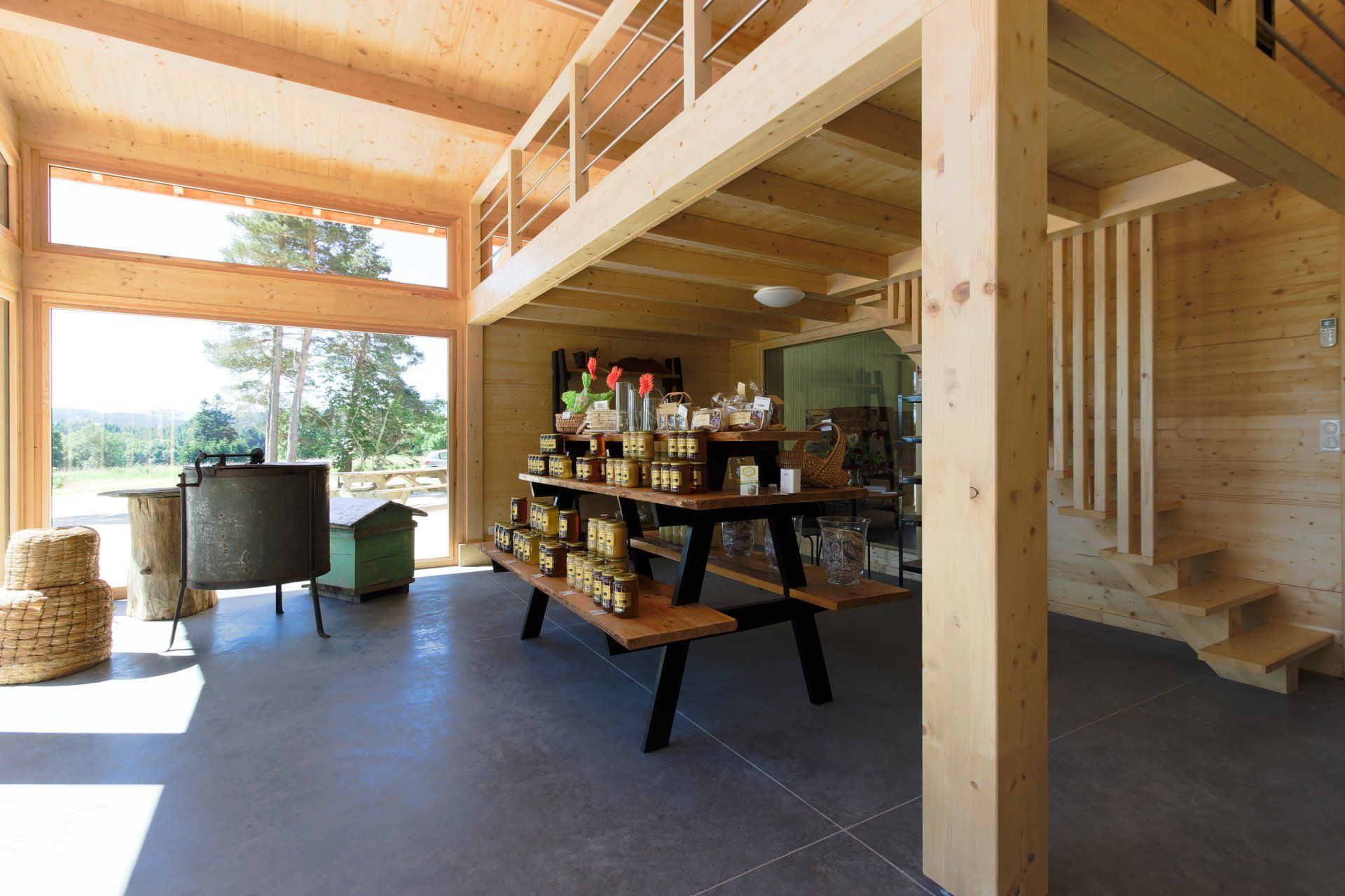 Intérieur en bois avec présentoir à marchandises, au deuxième étage, porte ouverte sur un paysage naturel.