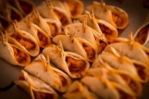 Hileras de tortillas enrolladas rellenas de crema de naranja, dispuestas muy juntas en una bandeja.