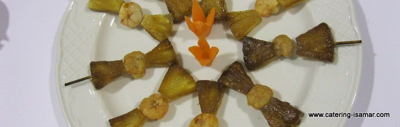 Rollitos de carne a la parrilla ensartados en brochetas y dispuestos en forma de estrella sobre un plato blanco.