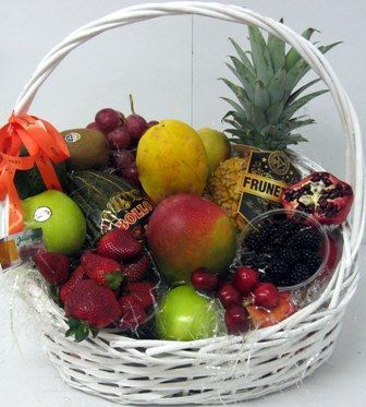 Cesta blanca con frutas frescas variadas, que incluyen piña, mango, uvas, fresas y manzanas.