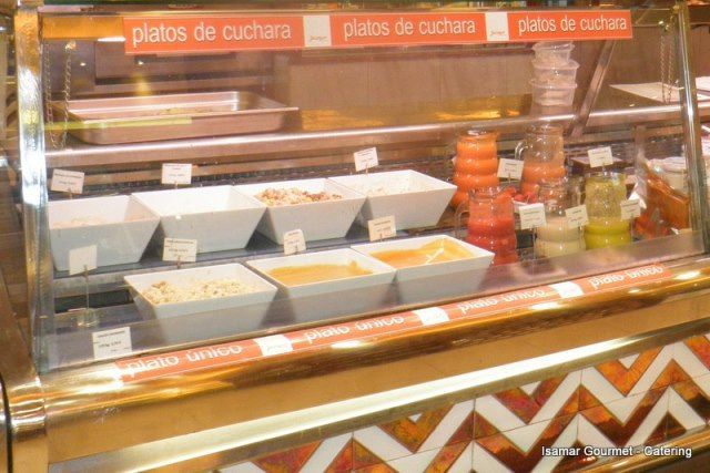 Vitrina de panadería con bandejas de postres y un letrero en español que dice “platos de cuchara”.
