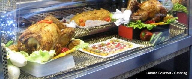Pollos asados y bandejas de comida expuestas en una vitrina de cristal con guarnición de lechuga.