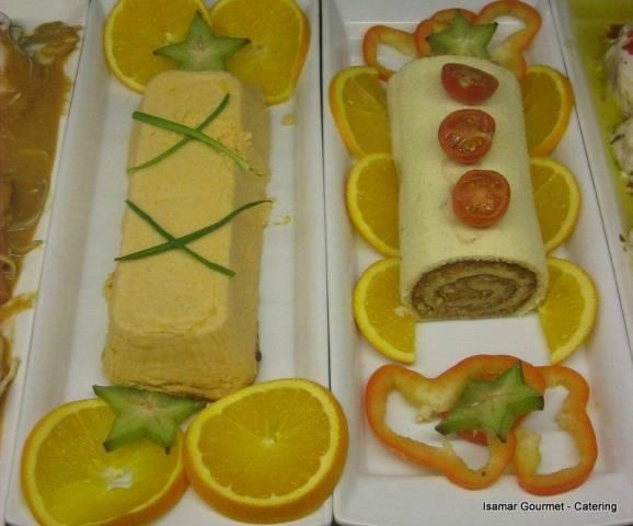 Platos enrollados salados y dulces decorados en una bandeja, adornados con rodajas de naranja y detalles de carambola.