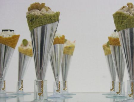 Conos altos plateados con tapas de gofre verde dispuestos sobre una superficie blanca.
