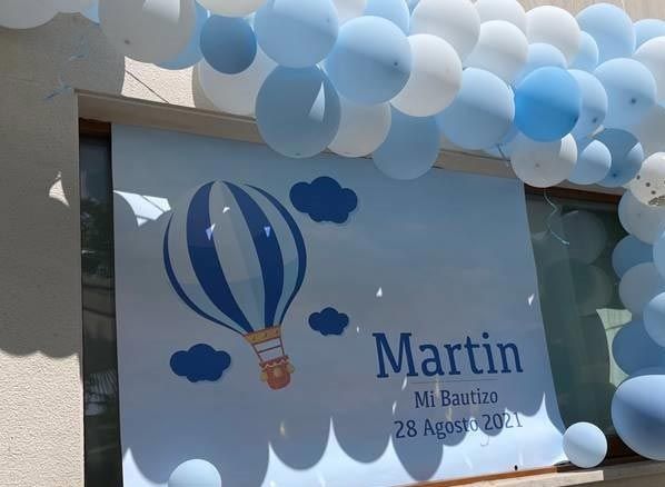 Letrero decorado con globos azules y blancos que dice 