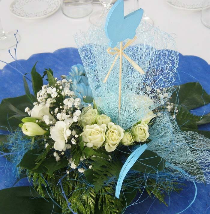 Arreglo floral azul y blanco con rosas, paniculata y cinta decorativa de malla azul.