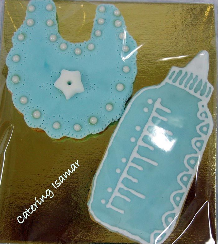 Galletas decoradas con baberos azules y biberones, envueltas en papel transparente.