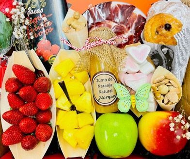 Surtido cestas de regalo de frutas coloridas con fresas, manzanas, mangos y chocolates envueltos en celofán.