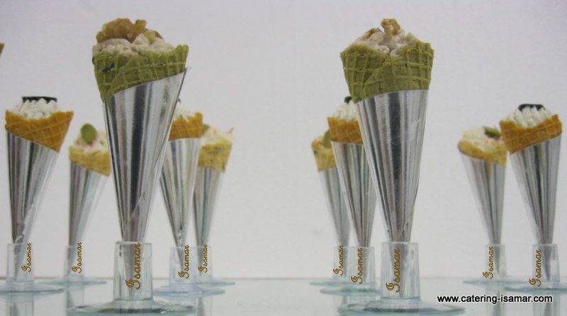 Pequeños manojos de patatas fritas en altos conos metálicos sobre una mesa de cristal, dispuestos en filas.
