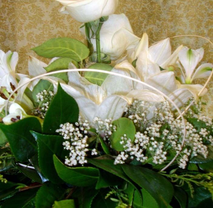 Rosas blancas y paniculata dispuestas con hojas verdes en un ramo floral