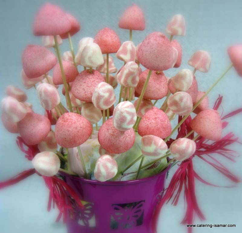 Piruletas rosas y blancas dispuestas en un cubo morado sobre un fondo azul pálido.